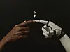 An image of two fingers — one human, one robot — touching, with a single musical note between them