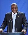 Ghana’s president, John Mahama, standing in front of a mic, laughing.