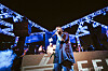 Sudanese rapper TooDope performs on a lit outdoor stage with blue lights and smoke effects.