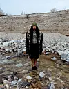 Dua Saleh is standing in a stream of water amongst rocks, wearing black socks.