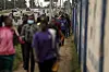 People walk along a Nairobi road during a transport strike, with traffic barriers and blurred pedestrians in view.
