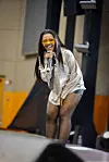 Liema Pantsi leans forward, singing into a microphone on stage.
