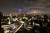Night skyline of Johannesburg with lit buildings and curving roads under clouds.