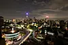 Night skyline of Johannesburg with lit buildings and curving roads under clouds.