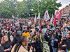 Large crowd of protesters gathered outside Leinster House in Dublin with banners and flags.