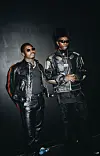 Blaqbonez and Asake are in black leather clothing and sunglasses, standing against a dark background.