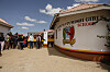 Parents and guardians gather outside Utumishi Girls Academy beside a school wall and crest in Gilgil, Kenya.