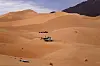 Tourists and vehicles on orange sand dunes near Iferouane in the Sahara Desert in northern Niger.