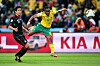 South African player Siphiwe Tshabalala, in yellow and green, strikes the ball past a Mexican defender during a World Cup match.