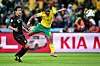 South African player Siphiwe Tshabalala, in yellow and green, strikes the ball past a Mexican defender during a World Cup match.