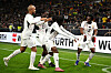 Ghana players in white celebrate a goal on the pitch during a match against Germany.