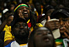 Ghana supporters in yellow and team colors react excitedly in the stands at Cardiff City Stadium.