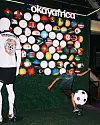 Indoor display wall covered with colorful soccer balls and Okaya Africa branding beside mannequin figures.