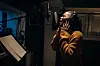 One woman, beautiful black female vocalist wearing headphones and singing into microphone in recording studio.