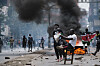 Protesters stand near a burning barricade with thick black smoke rising in downtown Nairobi.