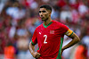 Achraf Hakimi, in a red jersey with the number 2, stands on the field during a semifinal match.