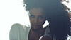 A screenshot from Tyla’s “Is It Love” video showing the singer in white and with full hair, staring into the camera.