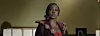 Woman speaking indoors near a podium in a dimly lit room.