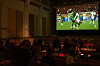 Crowd seated in a dark venue watches Morocco vs Senegal on a large screen at BASE Milano in Milan.