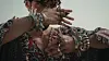 A man wearing large silver Amazigh bracelets on his wrists, resembling chains. His right eye is bruised.