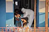 A worker in protective suit takes samples from a patient seated in a doorway at an Ebola treatment center.