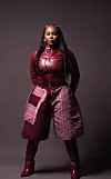 Studio portrait of a model wearing burgundy fashion pieces against a dark background.