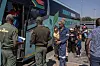 Border officials and migrants gather beside a bus during processing at the Beitbridge border crossing.