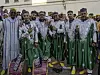 Seven men are posing for the camera; six of them are wearing green traditional Moroccan attire.