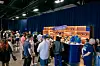 People gather around a Martell tasting bar at an event with blue branding and bottles on display.