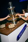 Martell-branded display table with chrome centerpiece and people holding drinks at TOTC 2026.