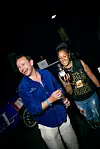 Two people smiling and holding a Martell bottle at a nighttime event.