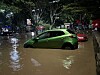 Green and red cars are partially submerged in floodwater on a Nairobi street at night.