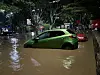 Green and red cars are partially submerged in floodwater on a Nairobi street at night.
