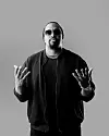 Black-and-white studio portrait of Navio, holding both hands open in front of a plain grey background.