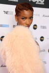 Ayra Starr poses on the MOBO Awards red carpet in a pale peach fluffy coat.