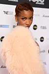 Ayra Starr poses on the MOBO Awards red carpet in a pale peach fluffy coat.