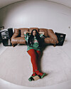 Shekhinah is sitting on the floor in front of a tan couch in a sparse living room.