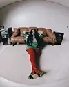 Shekhinah is sitting on the floor in front of a tan couch in a sparse living room.