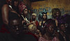 A group of people in colorful clothing and headwraps gathered closely indoors.