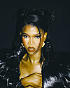 Close-up portrait of a woman in a black outfit against a dark background.