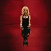 Zee Nxumalo wears a striking black dress against a white background in a promo image. Her hands are placed on a reflective surface, and the reflection is a dog.