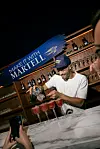 Marcio Ramos makes red cocktails at a Martell-branded bar display during TOTC 2026.