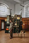 South Africa’s Yanga Chief standing beside stacked vintage speakers in a tall, wood-paneled hall.
