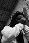 Blurred black-and-white portrait of Adey with her hands near her face.