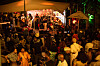 Crowd watching a live band perform on an outdoor stage at night.