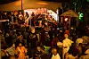 Crowd watching a live band perform on an outdoor stage at night.