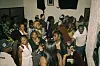 A lively indoor gathering with guests dancing, socializing, and holding drinks.