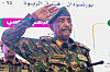 Abdel Fattah al-Burhan in camouflage salutes at an event in Port Sudan as Arabic signs appear in the background.