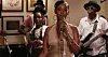 Sarah Hassan sings into a vintage microphone with a band performing behind her in a scene from Tides.