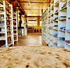 View down a wooden archive aisle with white shelves and tables in the distance.